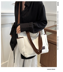 White canvas tote bag with brown straps and FASHION logo tag shown on a model
