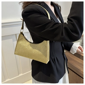 Borsa sottobraccio con paillettes dorate indossata con outfit da ufficio in interno luminoso