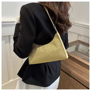 Gros plan sur la texture pailletée dorée du sac sous le bras au design géométrique