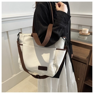 Minimalist off-white canvas tote bag with brown straps and spacious interior for daily use