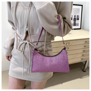 Détail du sac baguette à paillettes violettes scintillantes sur tenue beige