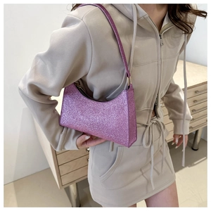 Détail du sac baguette à paillettes violettes porté par un mannequin en tenue décontractée