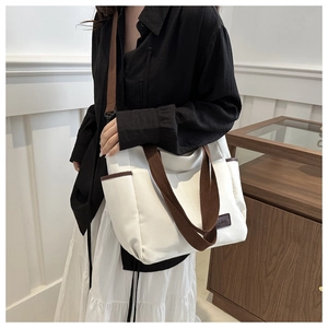 Detail of white canvas tote bag showing side pocket and brown leather label decoration