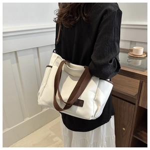 Detail of canvas tote bag with brown leather accents and fashion tag on side pocket