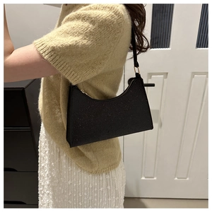 Détail du sac baguette noir à paillettes avec fermeture éclair incurvée et bandoulière en cuir