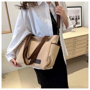 Lifestyle shot of model wearing the beige canvas tote bag with brown leather logo detail
