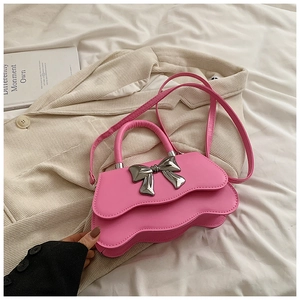 Vue détaillée du sac à main rose vif avec rabat ondulé et grand nœud métallique argenté