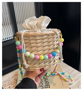 Détail du sac seau en paille tissée avec poignée en perles acryliques et doublure à cordon