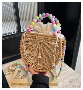 Detail of semi-circular rattan bag with colorful beads handle and drawstring lining