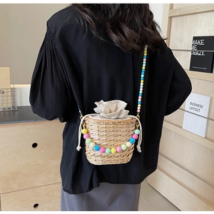 Détail du sac seau tressé avec bandoulière en perles colorées et doublure à cordon porté