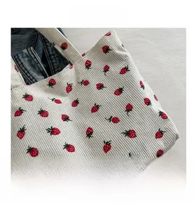 Detail shot of soft beige corduroy fabric featuring vibrant red and green strawberry patterns
