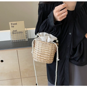 Gros plan sur le sac seau en paille avec bandoulière en perles et doublure en toile