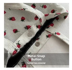 Close-up of magnetic snap closure on a corduroy tote bag with red strawberry print