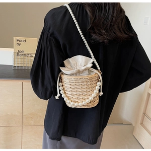 Détail du sac seau en paille tressée avec bandoulière perles et fermeture à cordon