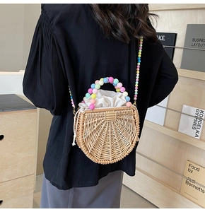Detail of a semi-circular woven rattan bag with colorful bead handle and canvas liner