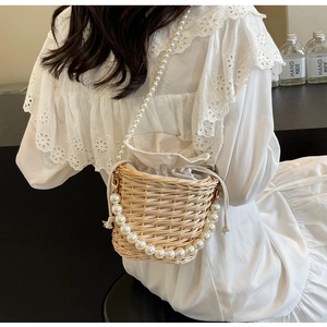 Détail du sac seau en paille tissée main avec doublure à cordon et deux chaînes en perles