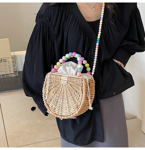 Detail of semi-circular woven straw bag featuring colorful macaron bead handle and strap
