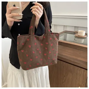 Close-up of brown corduroy tote bag featuring detailed red and green strawberry embroidery