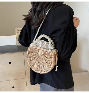 Detail of woven rattan semicircular bag with elegant pearl handle and drawstring closure