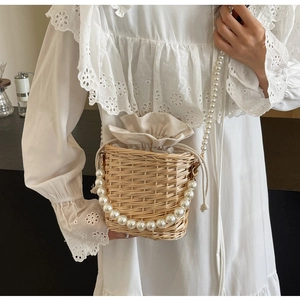 Détail du sac seau en paille avec chaîne de perles élégante et doublure à cordon serrage