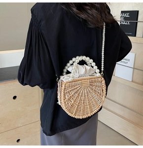 Detail of semicircular woven straw bag with pearl chain handle and drawstring lining