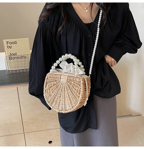 Detail of semi-circular woven rattan bag with elegant pearl handle and drawstring pouch