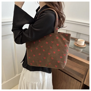 Detail of strawberry embroidery on brown corduroy tote bag showing material and texture