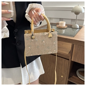 Detail of straw woven square bag with floral embroidery and yellow circular handle