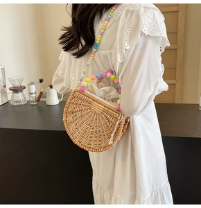 Detail of semi-circular straw bag featuring colorful acrylic bead chain and woven texture