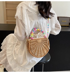 Detail of semi-circular woven rattan bag featuring colorful beaded handle and drawstring lining