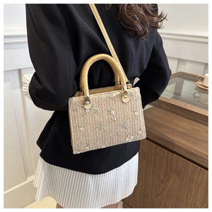 Detail of floral embroidery on a woven straw handbag with a chic leather strap