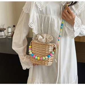 Détail du sac seau en paille tissé main avec bandoulière en perles colorées et doublure beige