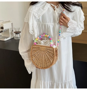 Close-up of semi-circular straw bag featuring colorful bead handle and drawstring liner