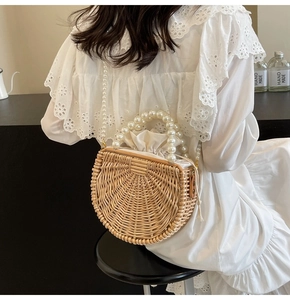 Detailed view of handwoven rattan bag with elegant large pearl handle and drawstring lining