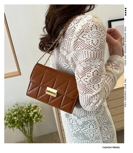Sac bandoulière marron matelassé avec chaîne dorée porté par un mannequin