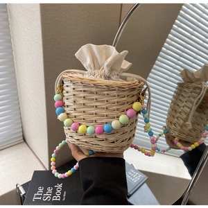 Détail du sac seau en paille avec poignée en perles acryliques et doublure en toile à cordon