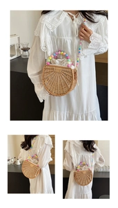 Detail of semi-circular straw bag featuring vibrant colorful bead handle and drawstring liner