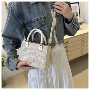 Detailed view of woven straw tote bag with delicate floral embroidery and leather handles