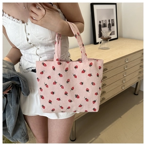Detailed strawberry embroidery on pink corduroy tote bag with soft fabric texture