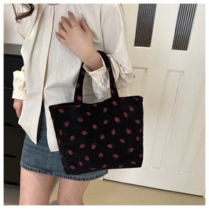 Corduroy strawberry print tote bag shown in use with white shirt and denim skirt