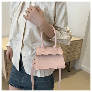 Detail of light pink mini bag with scalloped flap and golden metal clasp on shoulder strap