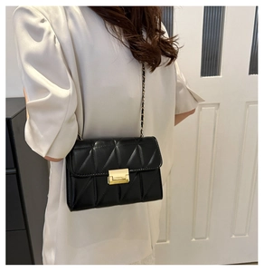 Détail d'un sac bandoulière matelassé noir avec fermoir doré et bandoulière chaîne