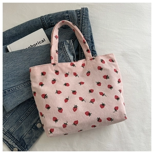 Detailed macro view of pink corduroy tote bag featuring fresh strawberry prints