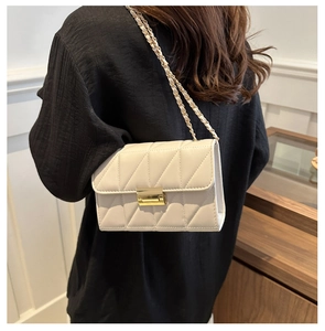 Gros plan d'un sac bandoulière beige matelassé avec chaîne dorée et fermoir carré