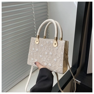 Close-up of woven straw tote bag with delicate white floral embroidery and sturdy top handles