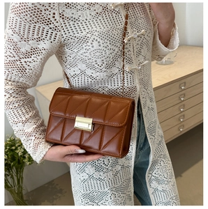 Sac bandoulière marron matelassé avec chaîne dorée et fermoir sur fond chaleureux