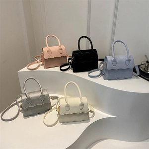 Mini scalloped shoulder bags in five colors on a layered white display stand