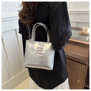 Dettaglio borsa shopper argento con trama metallica e ricamo rosso decorativo