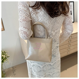 Dettaglio borsa a mano beige in pelle con ricamo rosa strive and optimism