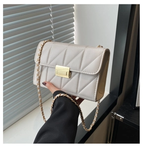 Détail d'un sac à rabat matelassé beige avec texture en V et boucle en métal doré